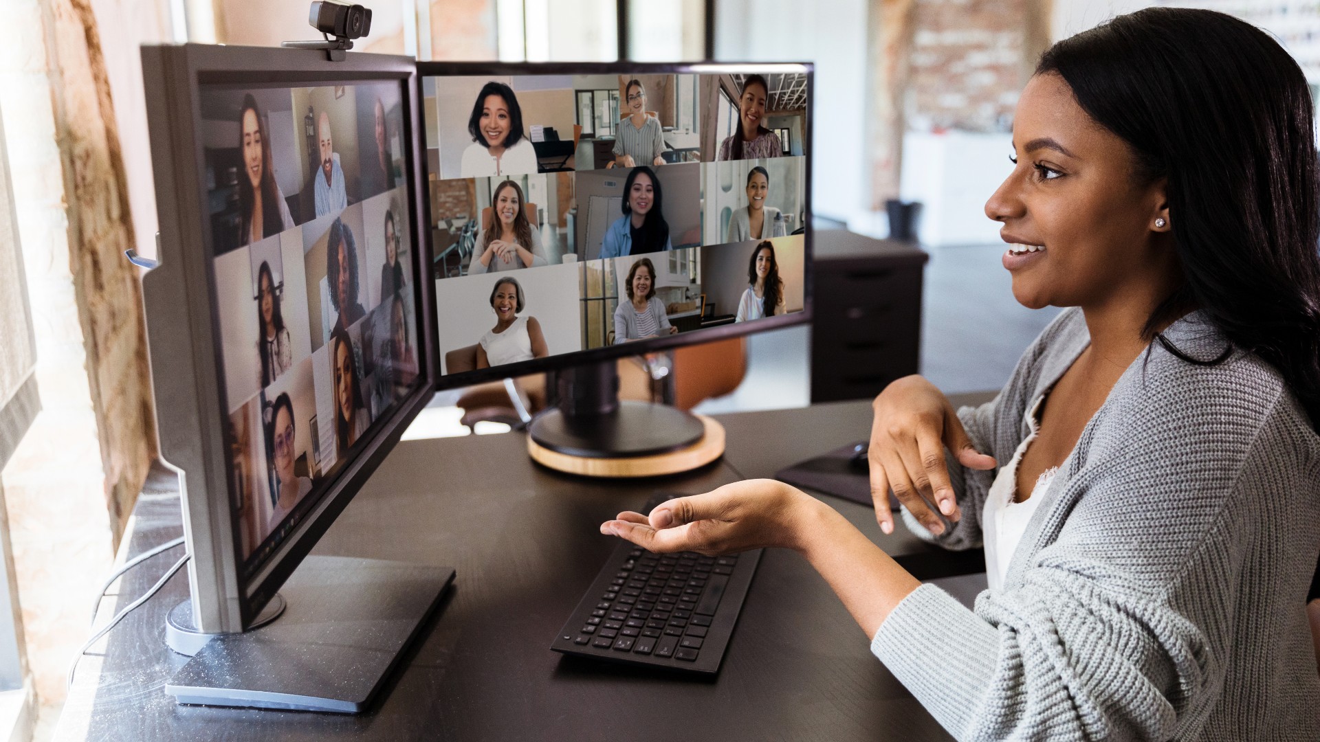 Woman on a video call with several other people showing on the monitors.