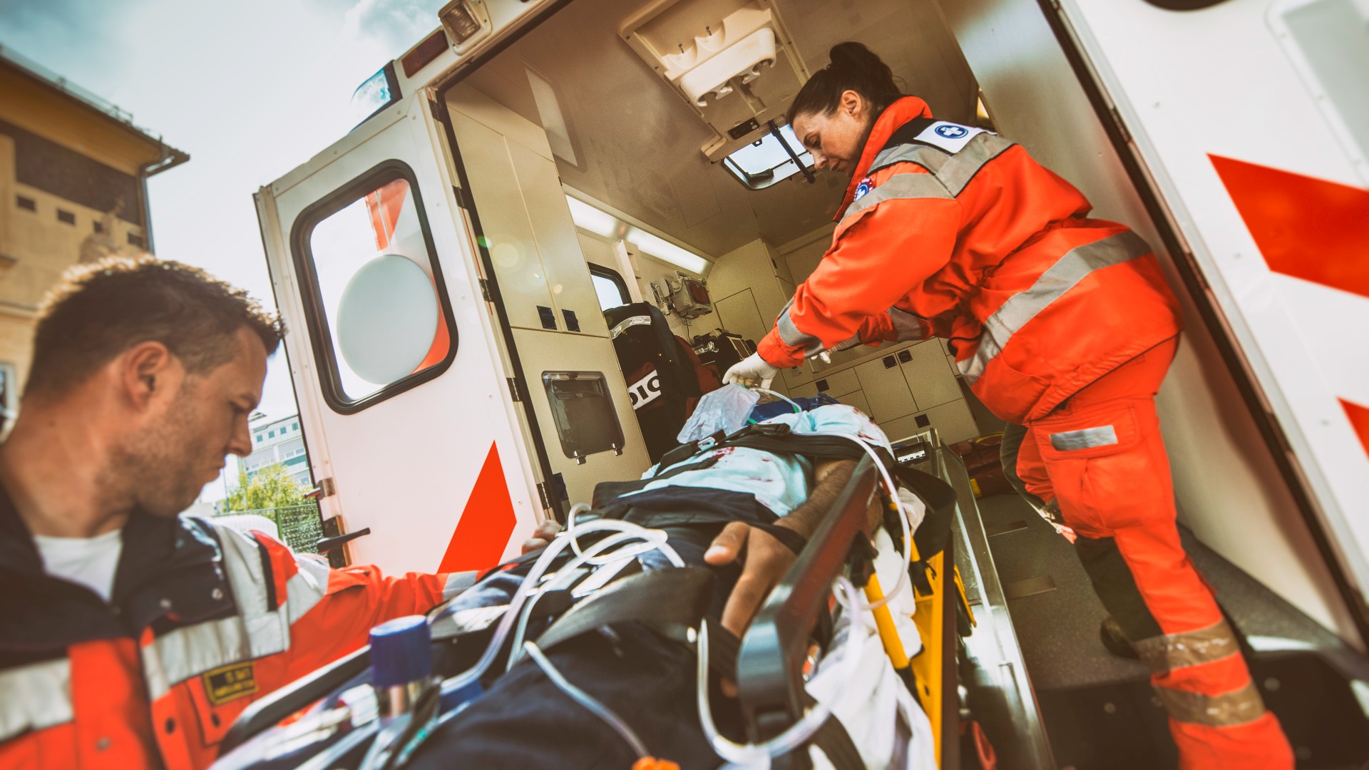 Two EMT workers loading a patient into an ambulance