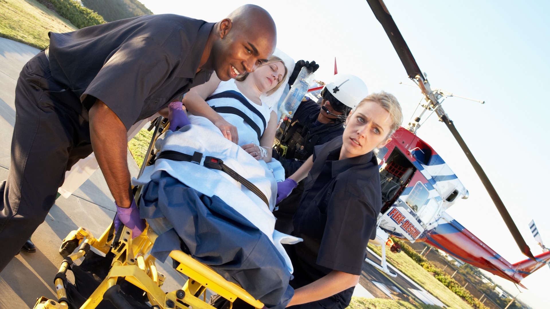 Two EMTs moving a patient on a stretcher from a helicopter