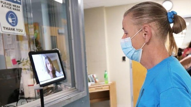 nurse in mask talking to patient on screen
