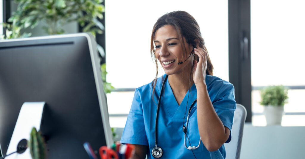 Female doctor talking with earphone while explaining medical treatment to patient through a video call with computer in the consultation.