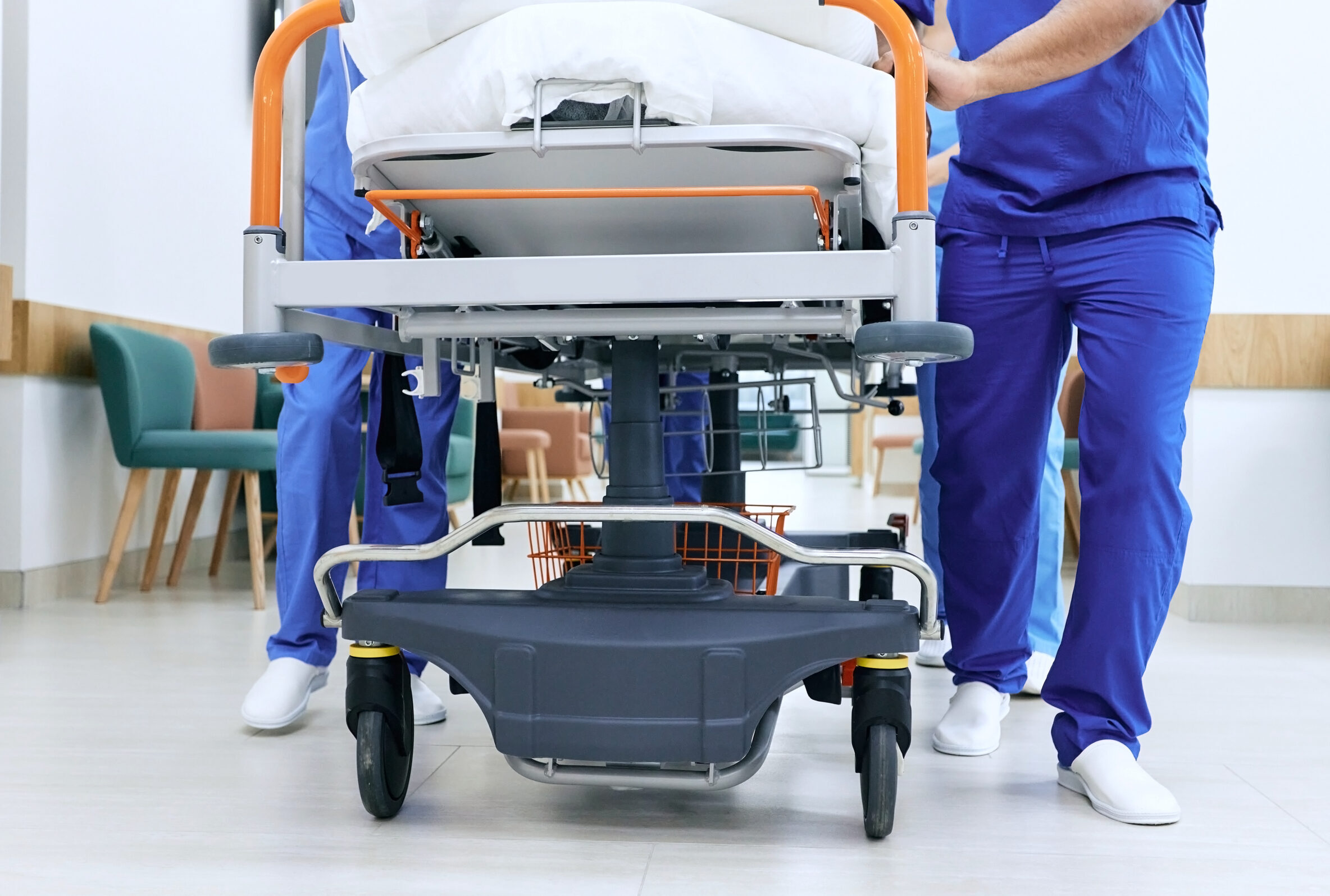 Medical staff pushing patient on medical gurney at emergency department, bottom view. Hospital emergency and healthcare workers