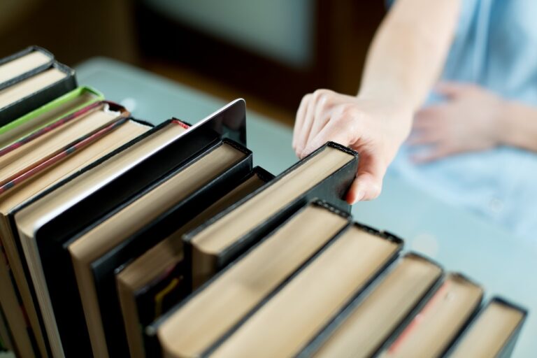 Girl chooses an old paper book instead of a tablet, which stands next to in a row of books
