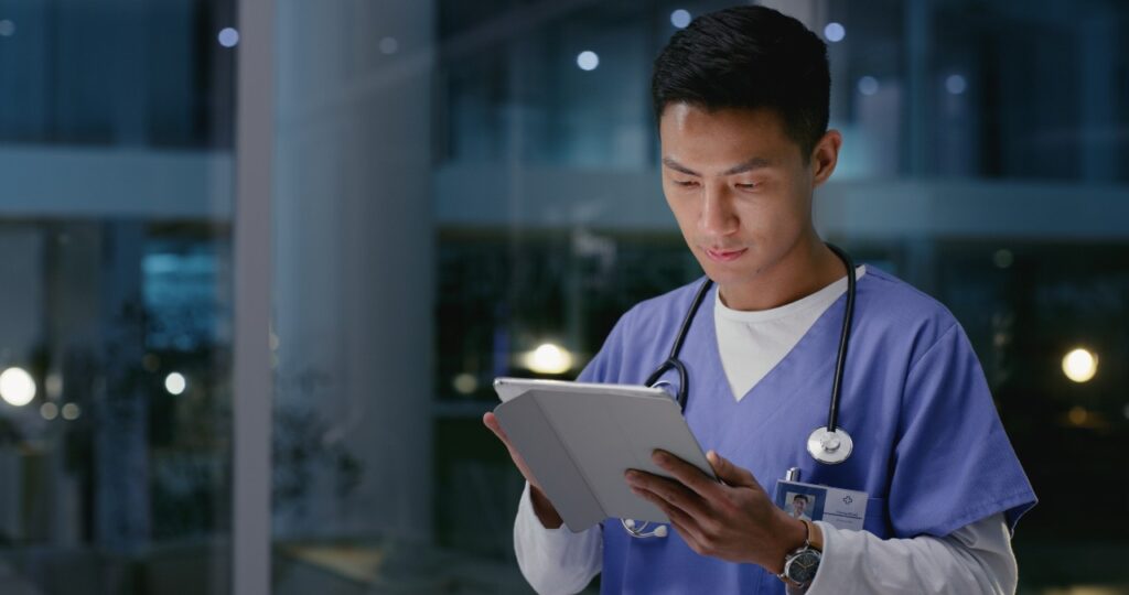Healthcare, man and nurse with tablet for research, diagnosis information and reading at night. Late, male person and medical worker with digital for scrolling report, review treatment and hospital