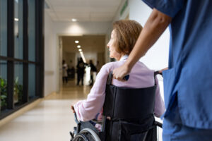 Rear view of a nurse pushing a senior woman in a wheelchair at the hospital