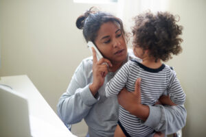 Mom on the phone while holding young child.
